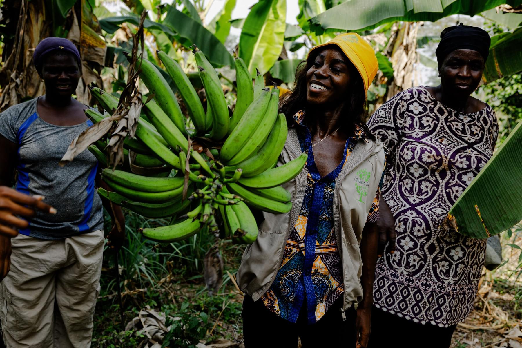 Three people at a banana farm smiling